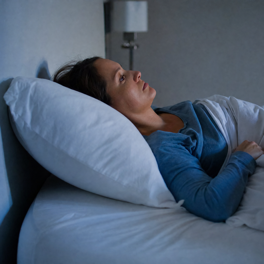 Woman awake at night on an ordinary puffy pillow, neck bent